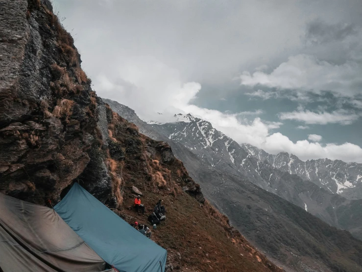 mountains and a camp is seen from the bottom of a cliff