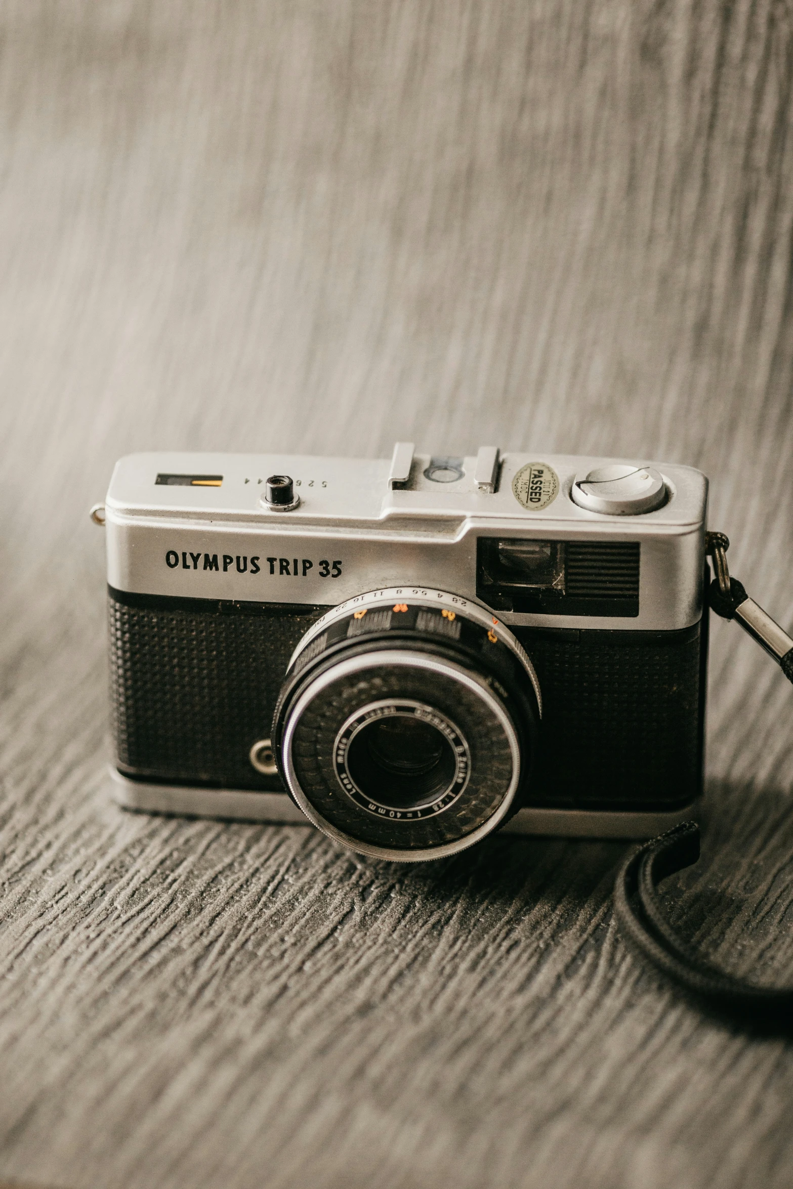 a camera laying on a brown wooden floor next to a black and white pograph