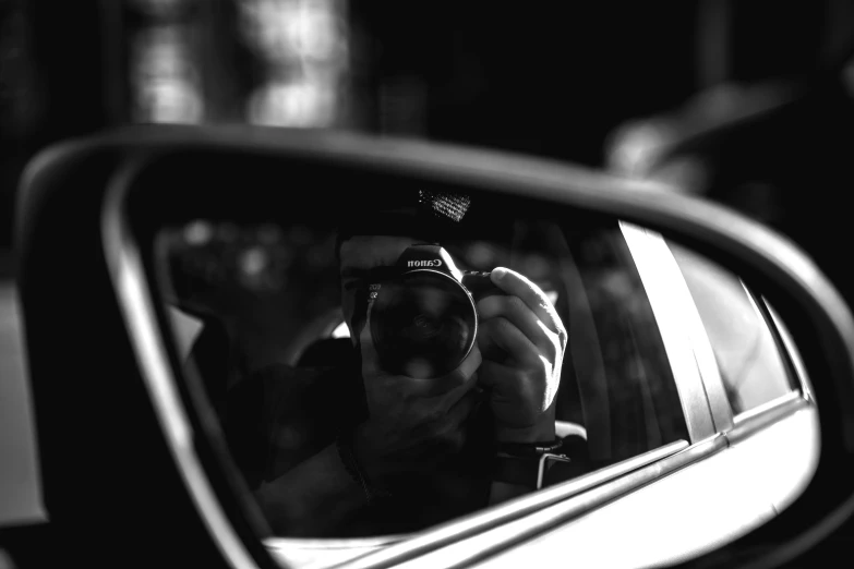 a man taking a selfie in a rear view mirror