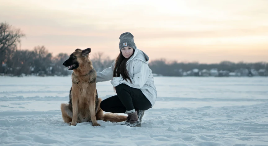a lady and a dog sit in the snow