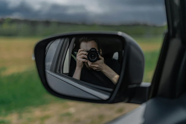 a man taking a po through the side mirror of a car