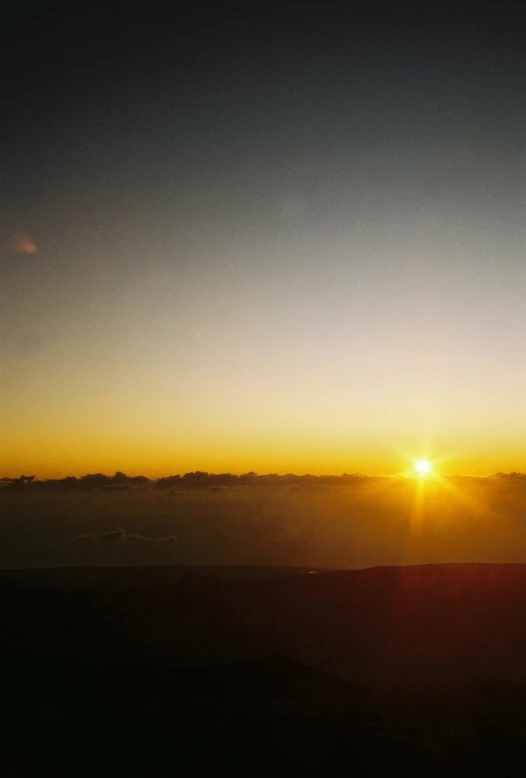 the sun rises above the clouds on top of a mountain