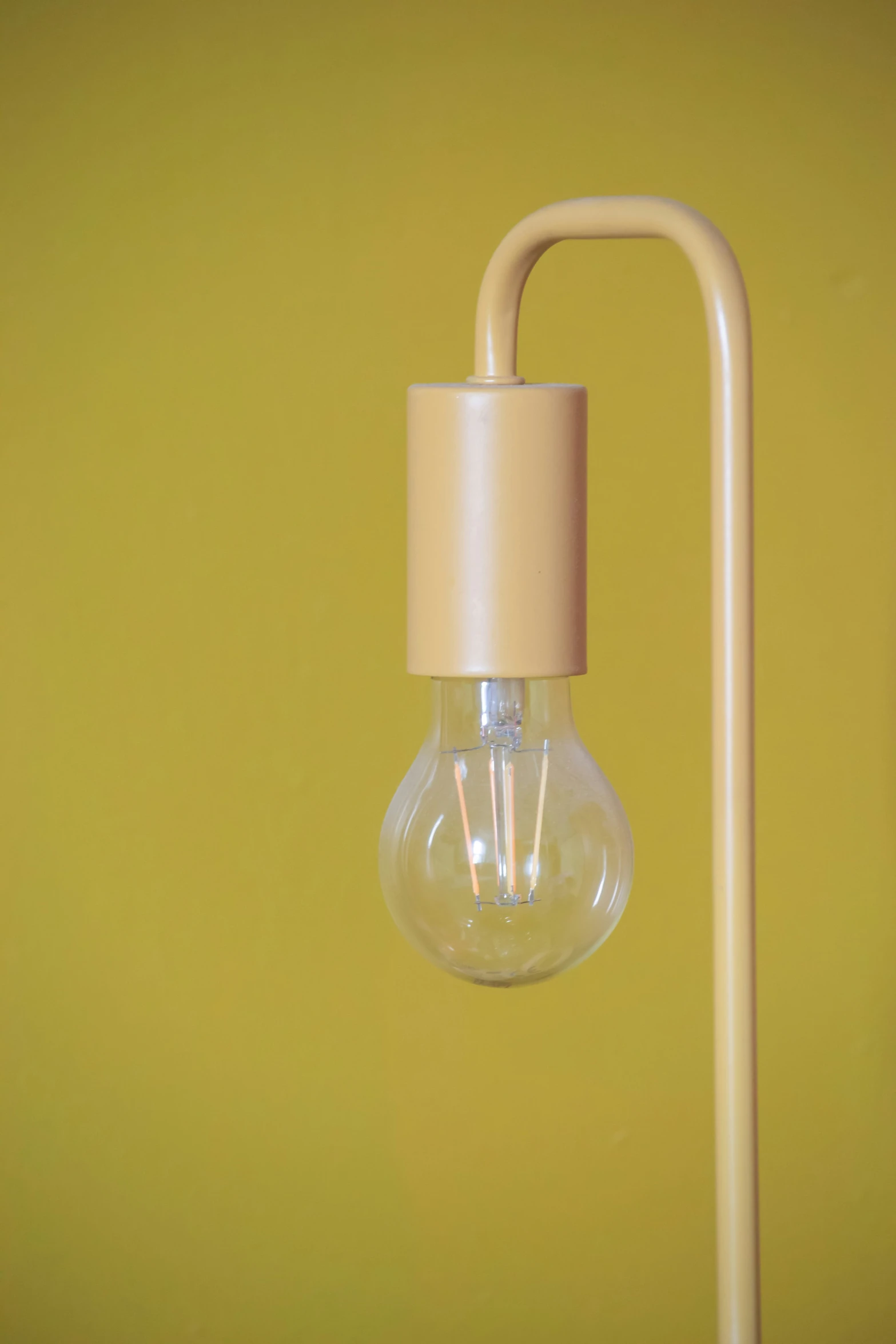 a light fixture is standing against a yellow wall