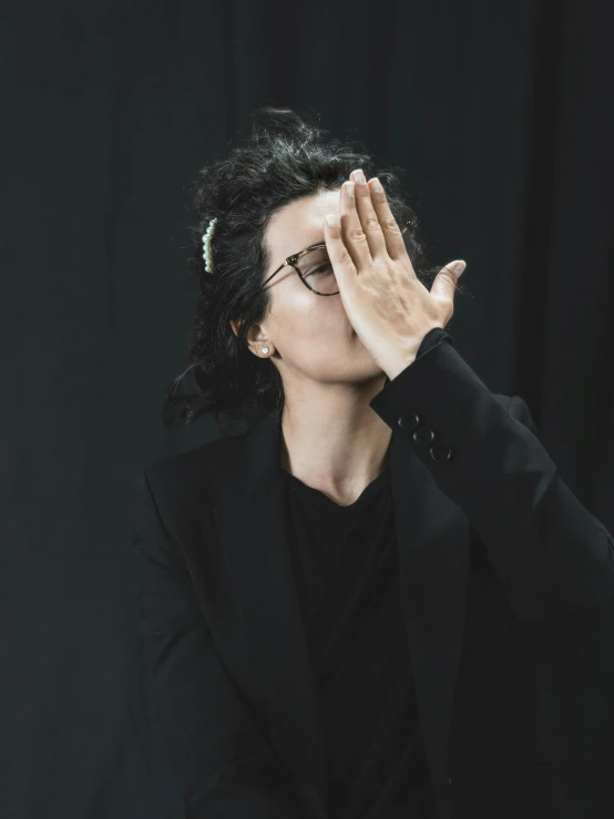 a woman wearing glasses holding her hands to her face