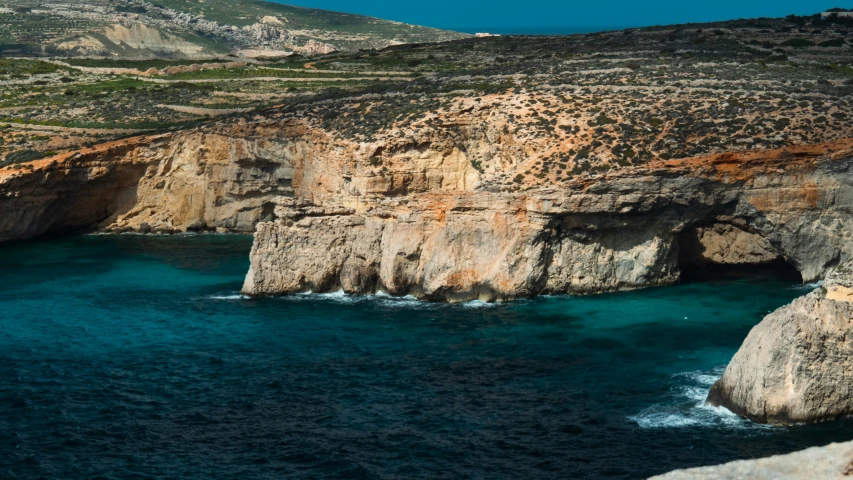 rocky cliff overlooking blue ocean in a mountainous area