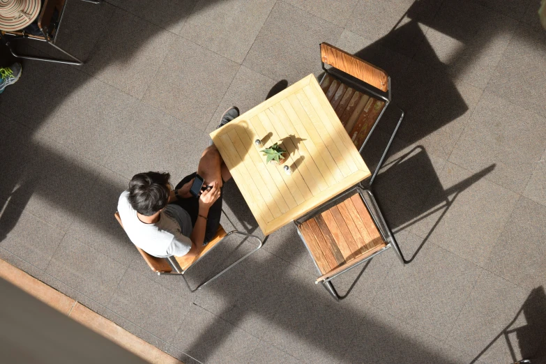 a man sitting at a table on top of an empty chair