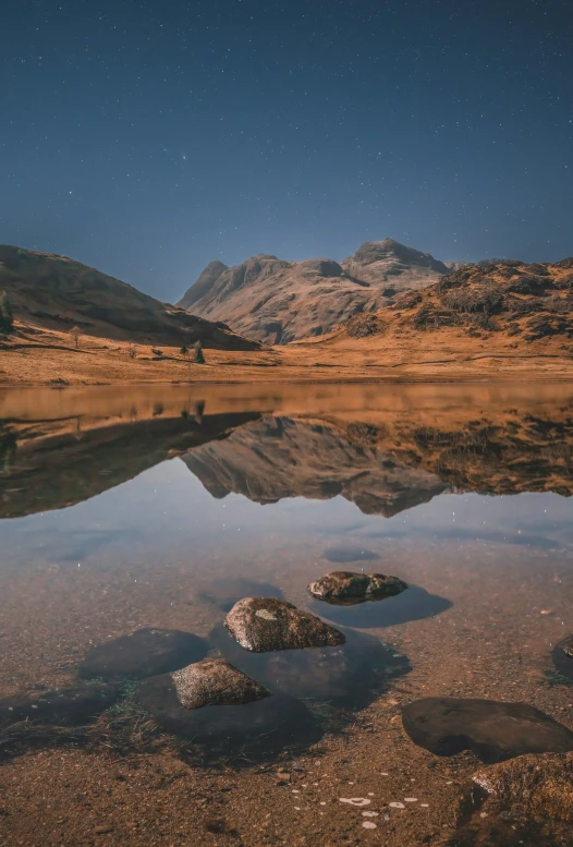 some rocks in the water some hills and stars