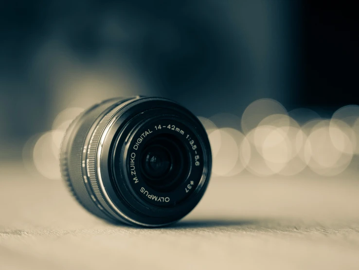 a camera lens sits on a table against a light - colored background