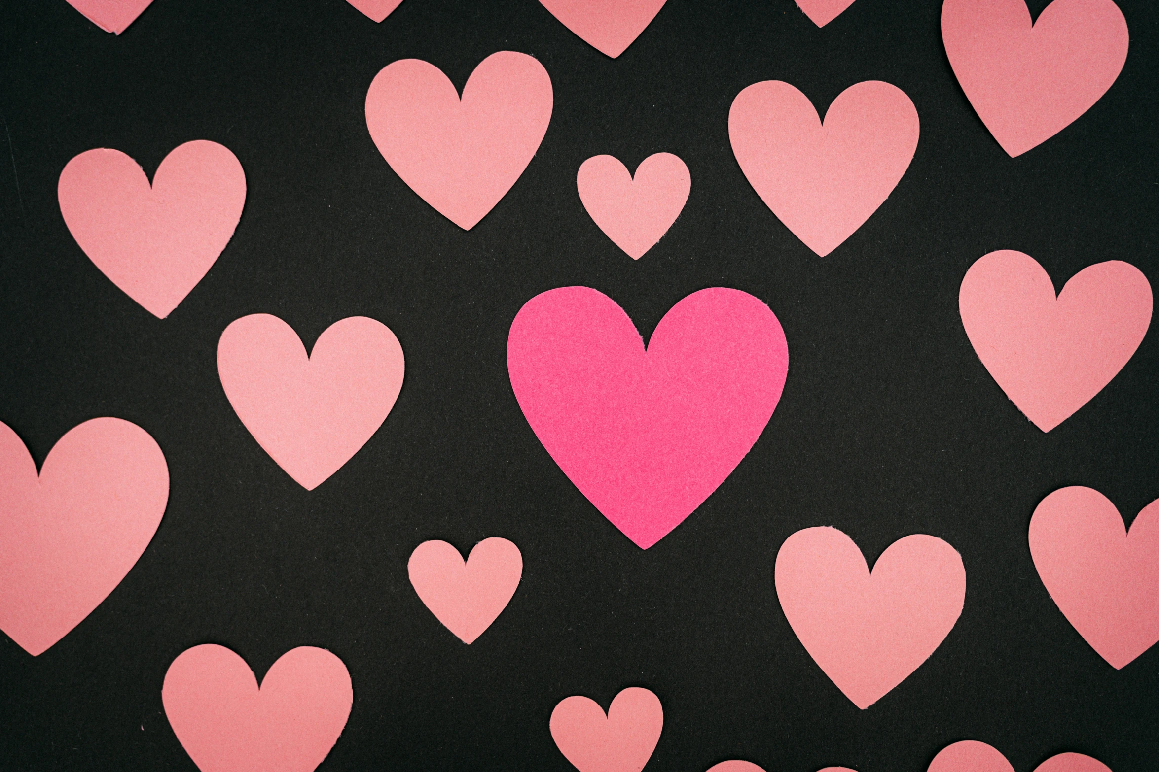 pink hearts shaped into a group of smaller ones on a black background