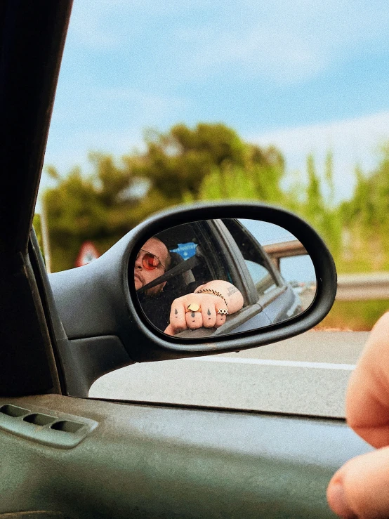 a car mirror with reflection of someone taking a selfie