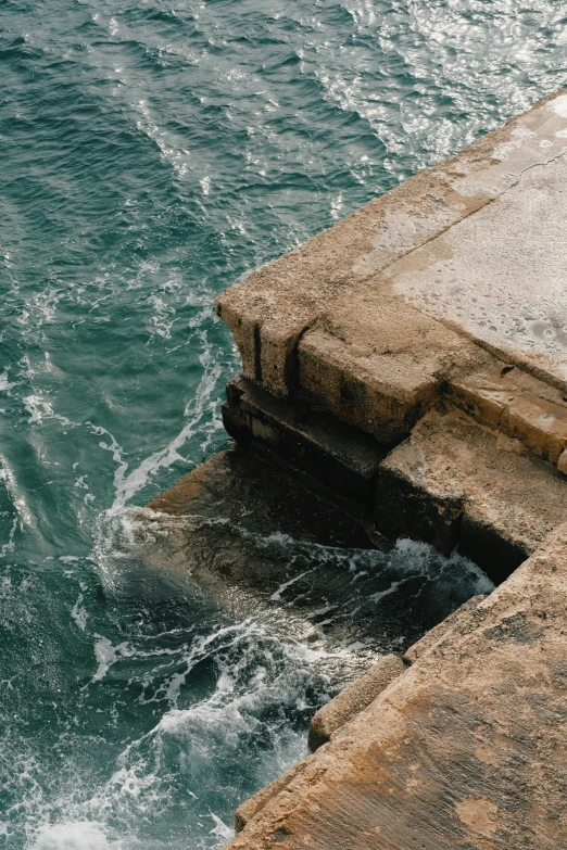 the water is blue and green next to a rock wall