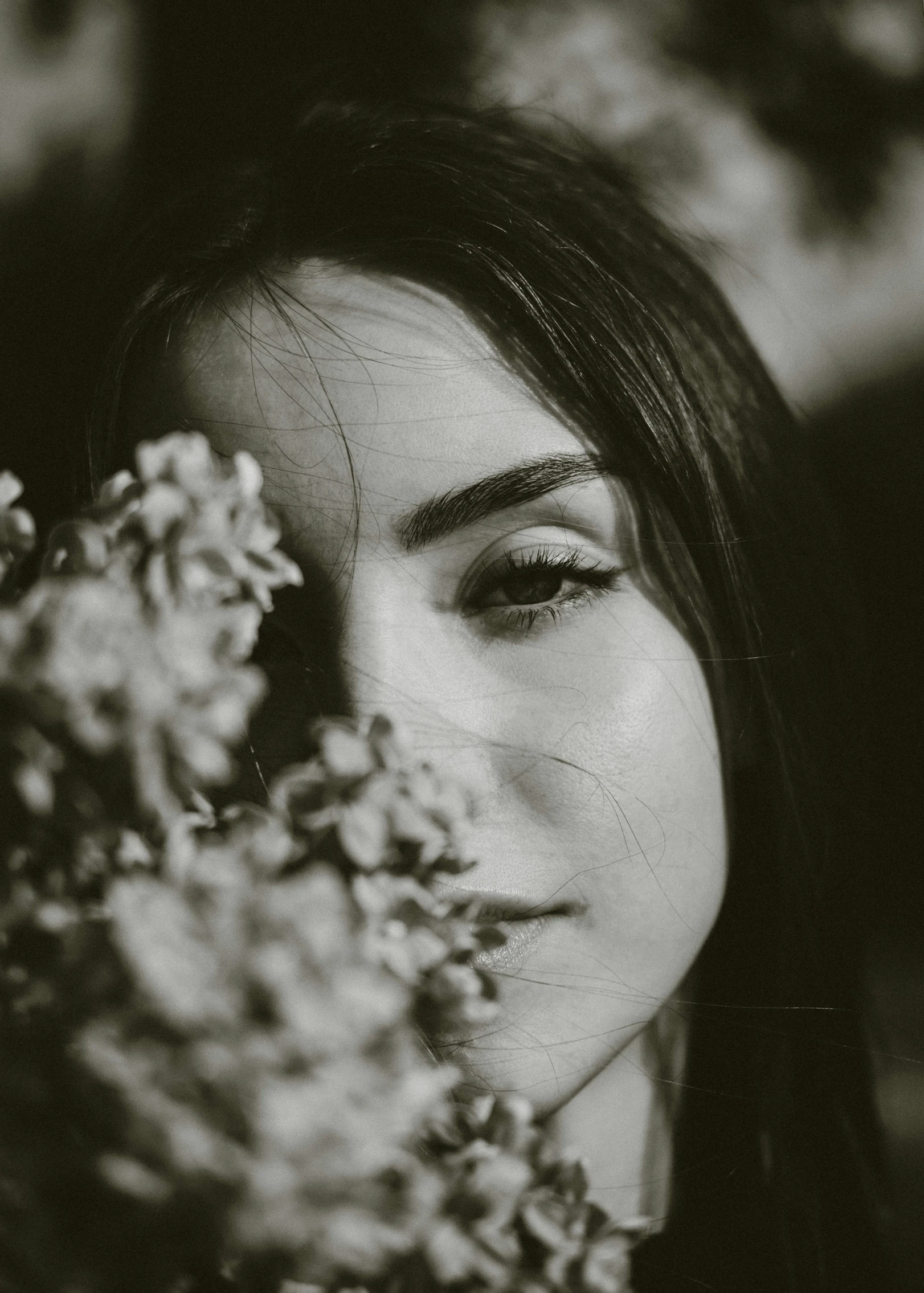 black and white po of young woman smelling flowers