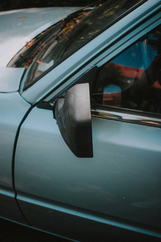 a green car is shown with a reflection of people on it