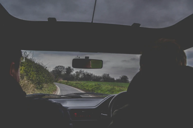 two people sit behind the wheel of a vehicle, with a green and black fields