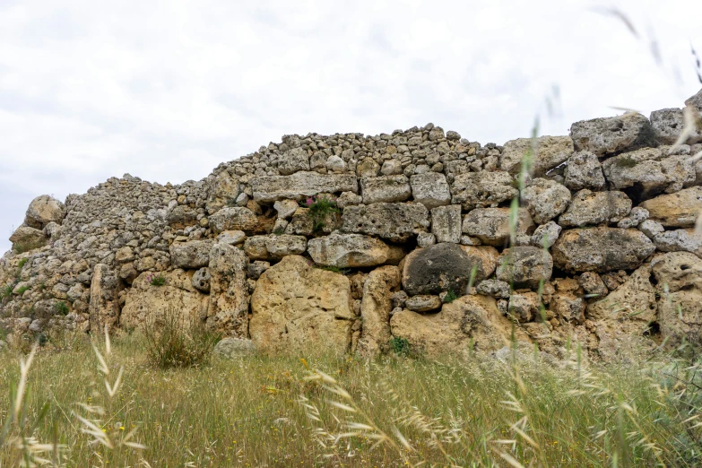 a stone wall sitting between grass and a hill