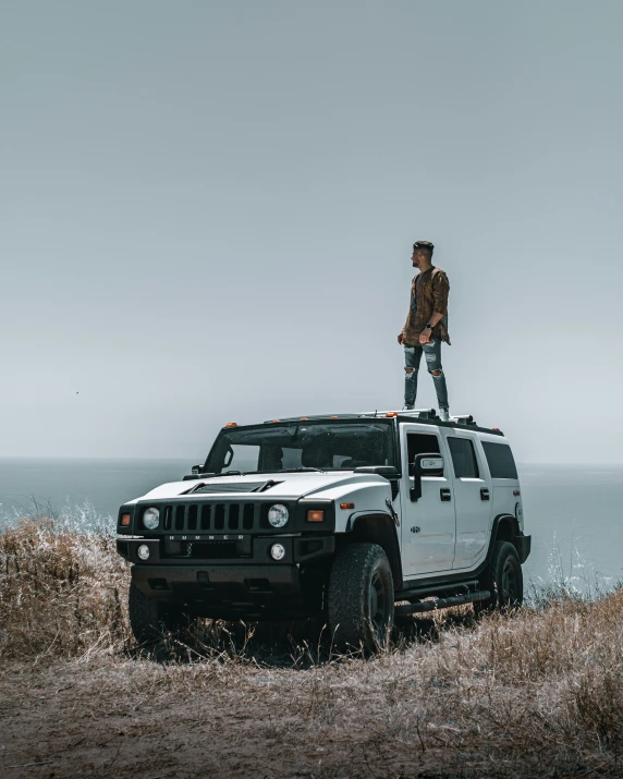 a man stands on the top of a hummer