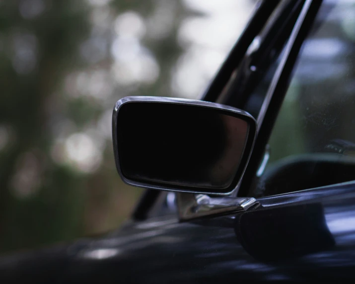 a black car with trees in the background