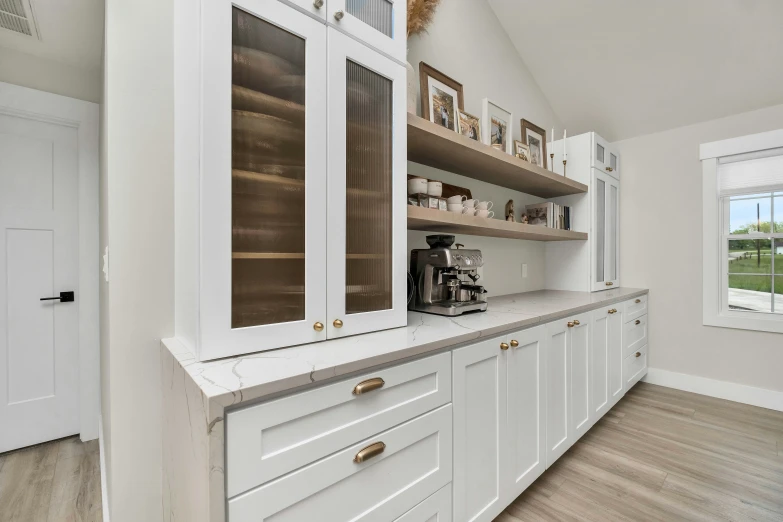 a kitchen with a wide window next to white cabinets