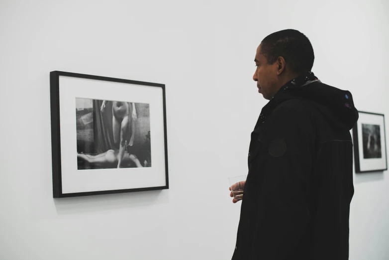 a man is looking at his artwork on the wall