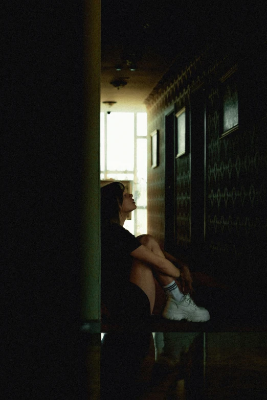 a woman is sitting on a bench in the dark