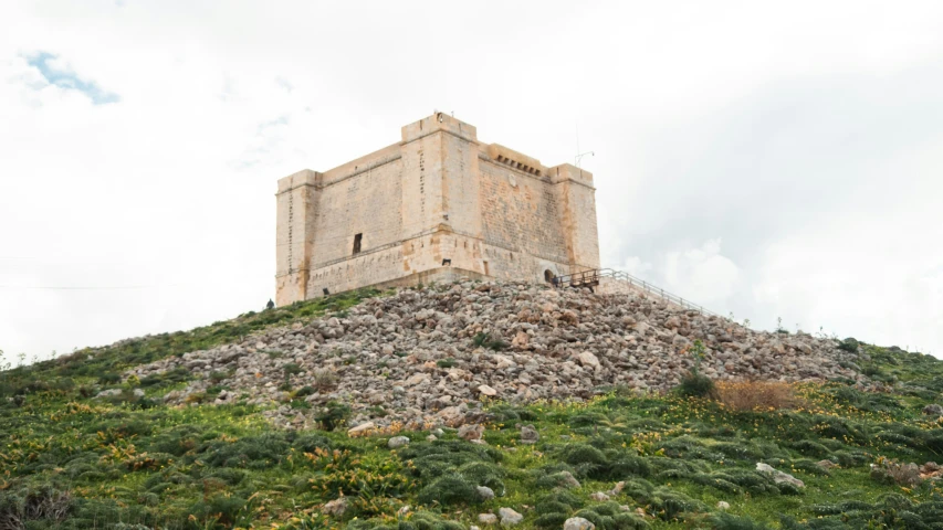 a stone tower on a hill under a cloudy sky