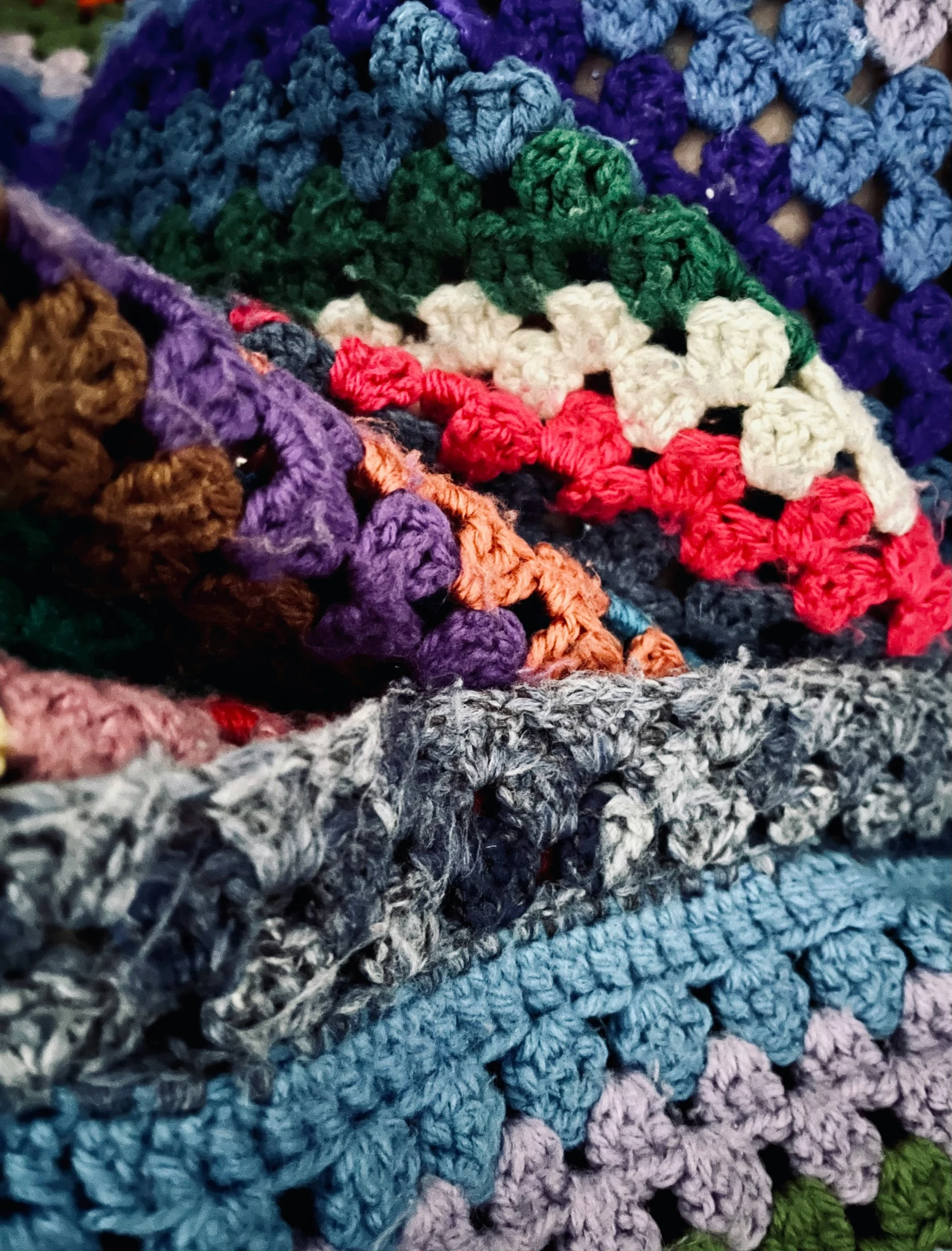 a crocheted multi - color granny afghan with a large amount of colorful, triangular motifs