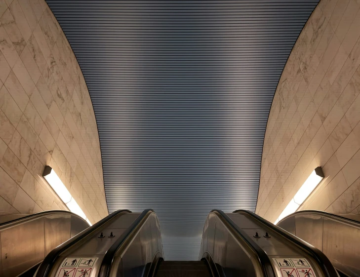 a pair of escalator next to a wall