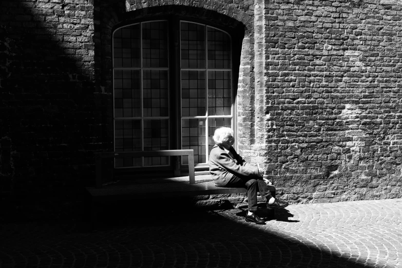 the woman sits on a bench by the window