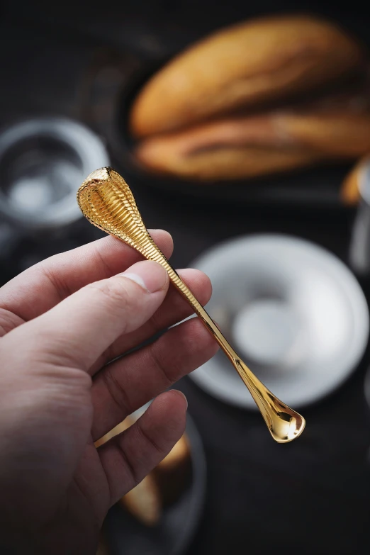 a small hand holding a large spoon with gold leaves