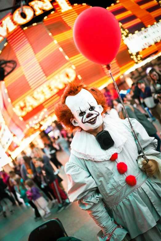 a person in clown makeup holding red and white balloons