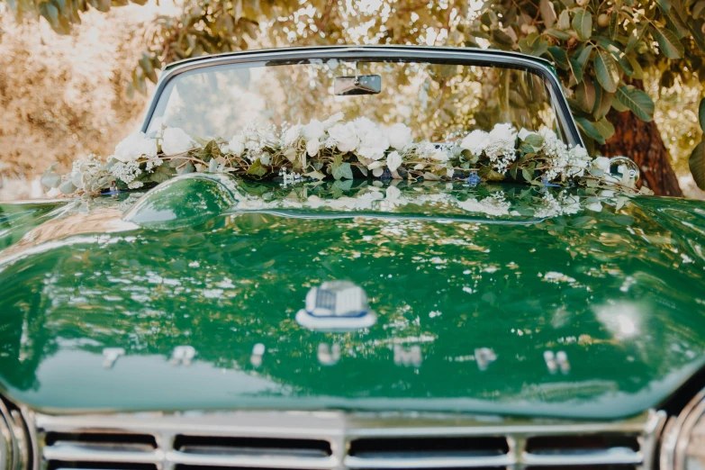 an old green car is decorated with white flowers