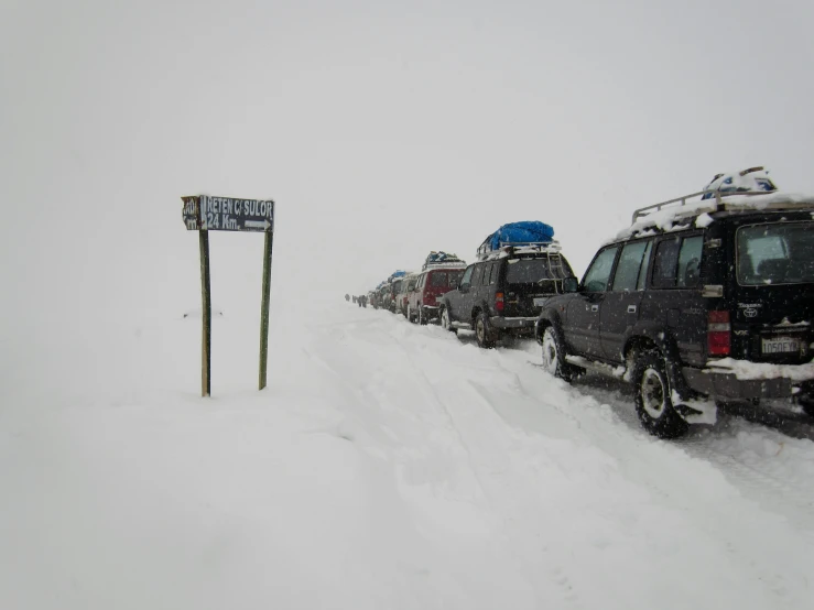 a group of cars parked next to one another on a snowy hill