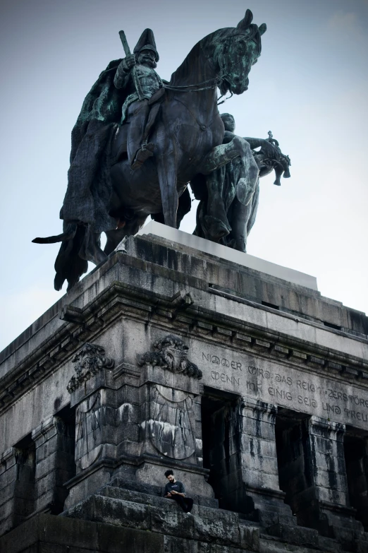 a statue in a stone base that is near a building