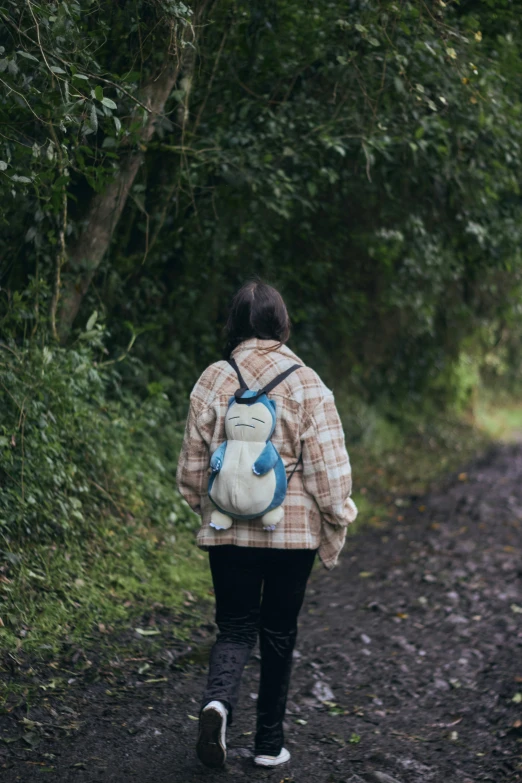 the back of a woman who is walking down a wooded path