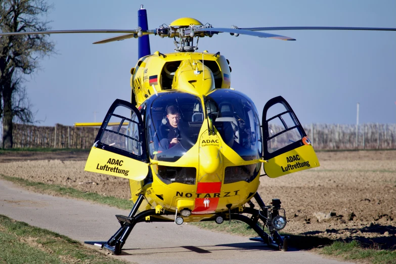 a yellow helicopter with a woman inside sits on the ground