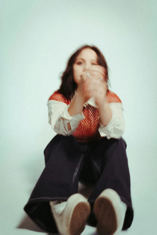 a woman sitting on the floor in an orange shirt and black pants