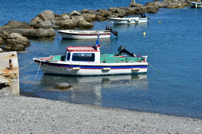 boats moored in the water beside large rocks