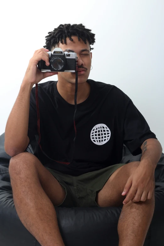 a man in black shirt sitting on couch taking pictures