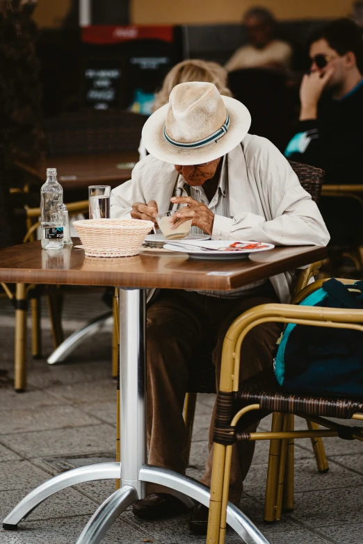 an old man is sitting at a table using a cellphone