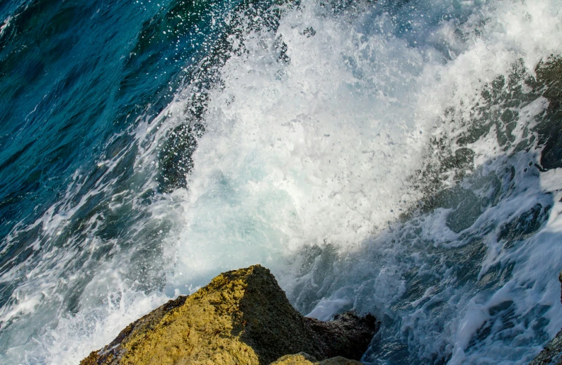 a large wave breaking over a rocky cliff