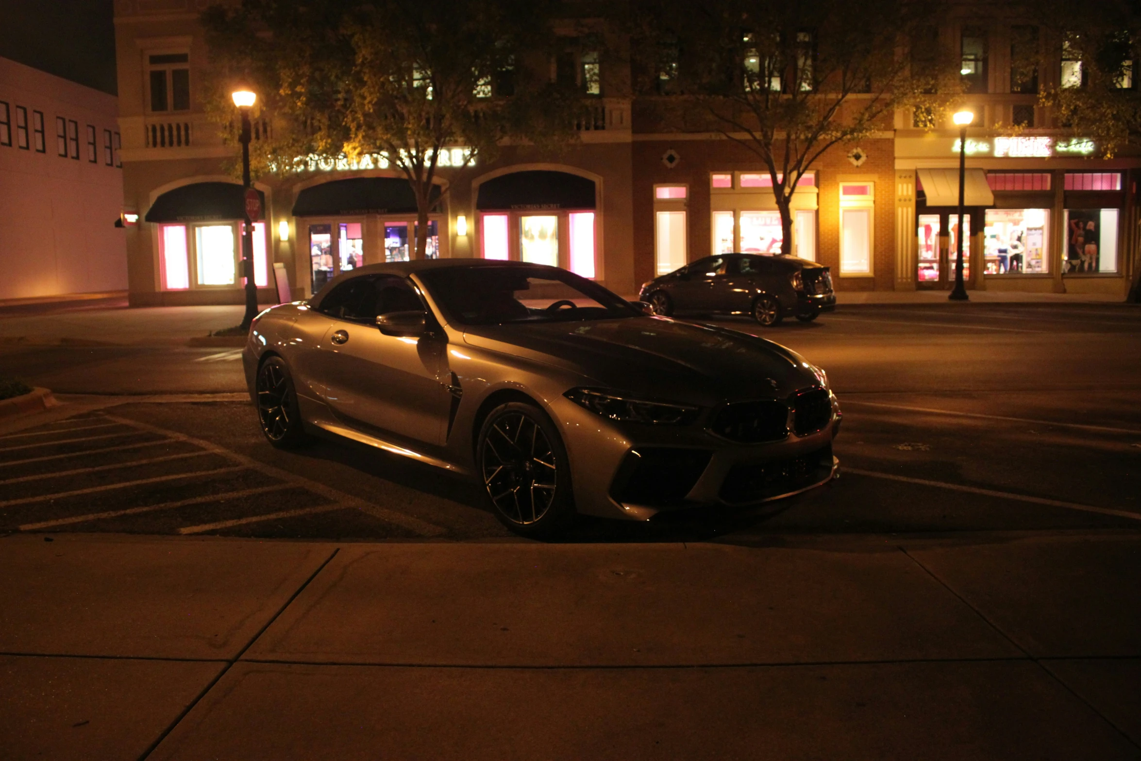 two fancy automobiles are parked on a parking lot