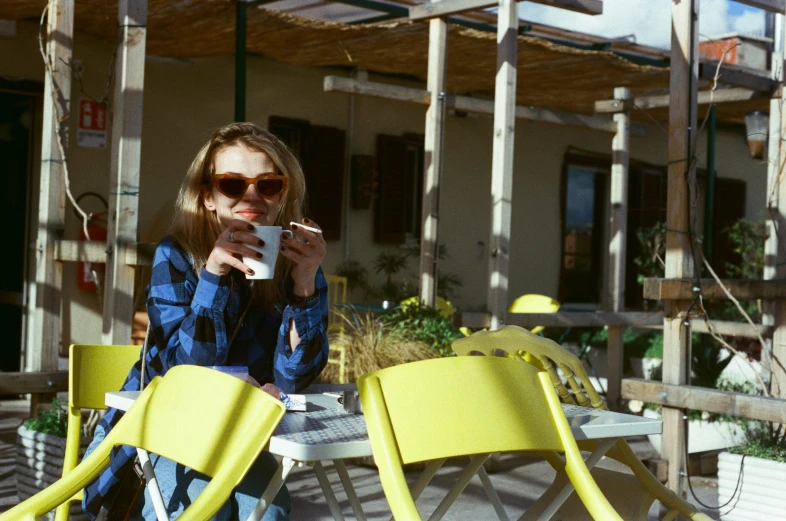 the woman is sitting outside and taking a drink