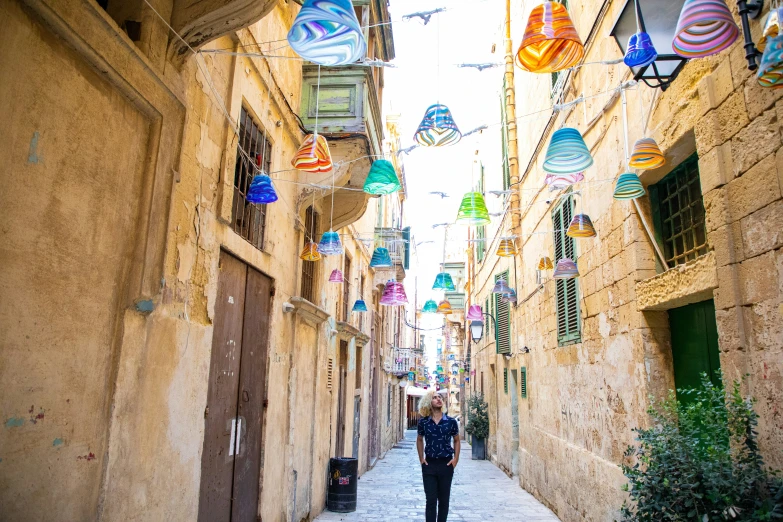 a man walking down an alley way next to tall buildings