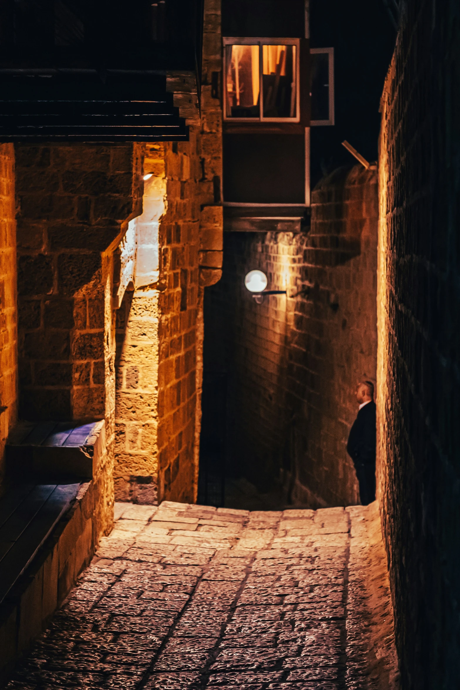a person is standing out from the dark in an alleyway