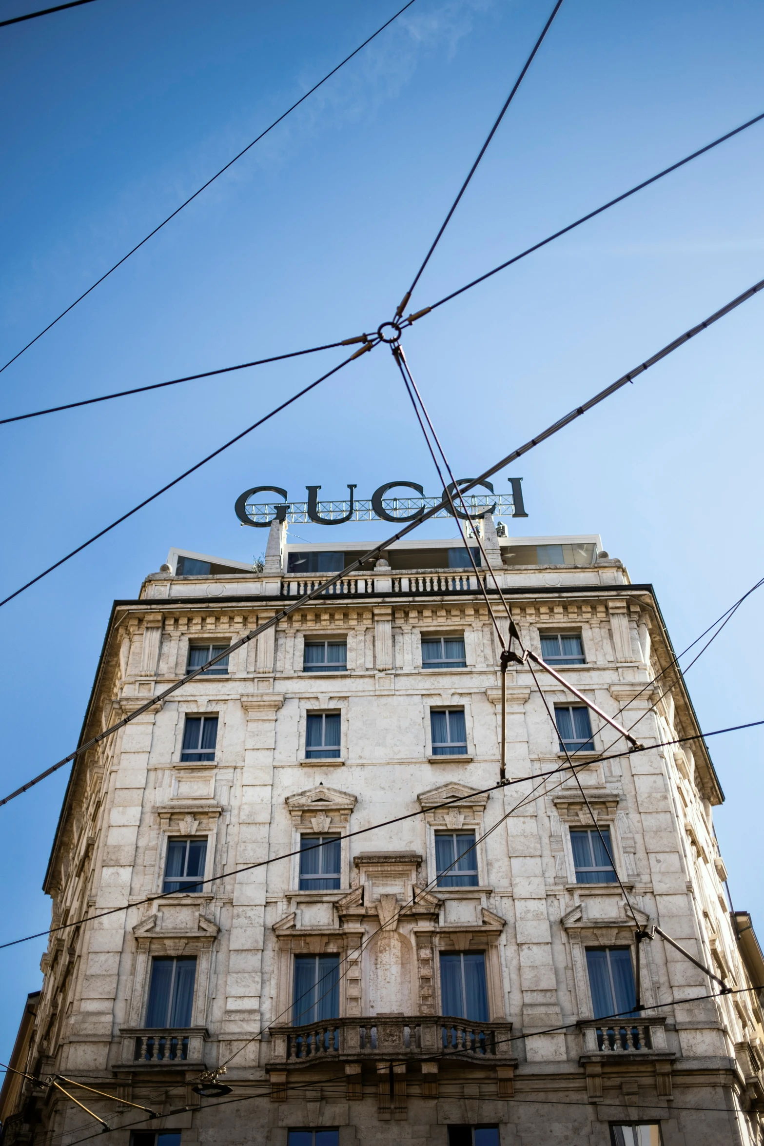 a very tall building under power lines in front of a clear sky