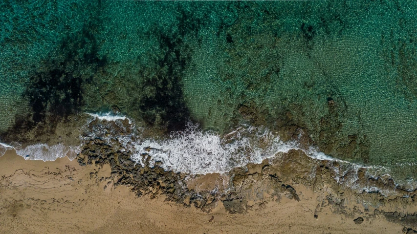 an aerial view of waves crashing to the beach