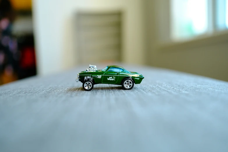 green toy car sitting on top of a wooden table