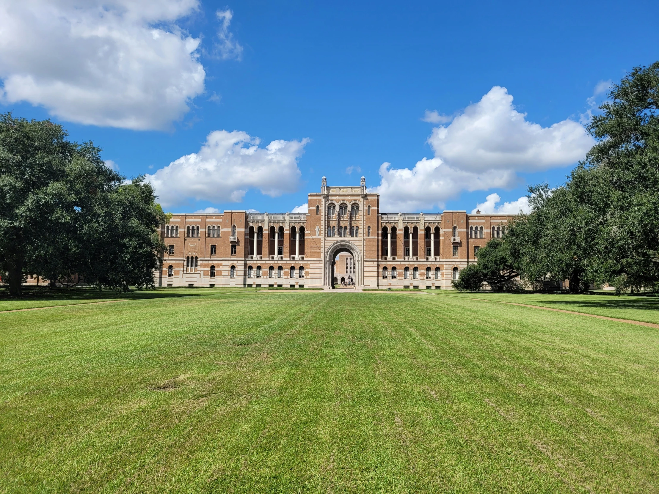 a beautiful brick building with green grass and trees