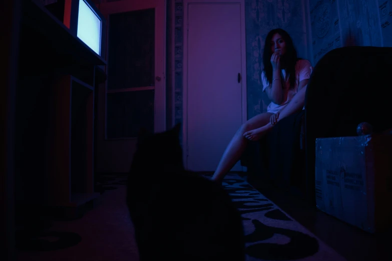 a woman kneeling on the floor next to a black cat