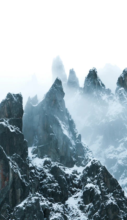 mountains covered in snow and fog on a cloudy day